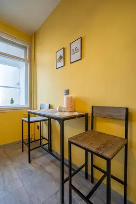 two tables and chairs in a room with a yellow wall at Golden Glow Residence in Sofia