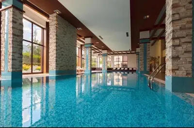 a large swimming pool with blue water in a building at Terra SP apartments-Razlog in Razlog