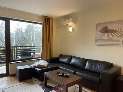 a living room with a leather couch and a large window at Terra SP apartments-Razlog in Razlog