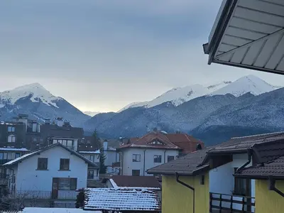 a city with snow covered mountains in the background at Cтаи за гости Бърдареви in Bansko