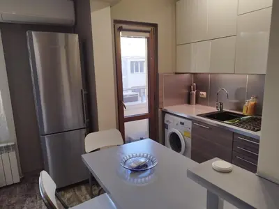 a kitchen with a stainless steel refrigerator and a table at Heart of Pernik apartment in Pernik