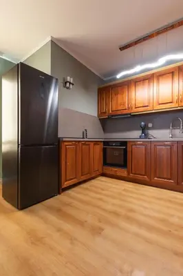 a kitchen with a stainless steel refrigerator and wooden cabinets at Cedar Lodge III 2 BDRM Flat B12 in Bansko