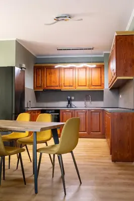 a kitchen with wooden cabinets and a table and chairs at Cedar Lodge III 2 BDRM Flat B12 in Bansko