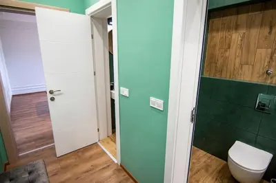 a bathroom with a toilet and a green wall at Jungle apartment in the center in Sofia