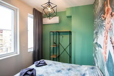 a bedroom with green walls and a bed and a chandelier at Jungle apartment in the center in Sofia