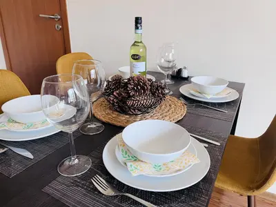 a table with plates and glasses and a bottle of wine at Mountain Cedar Pine 1 BR Apt near Ski Gondola in Bansko
