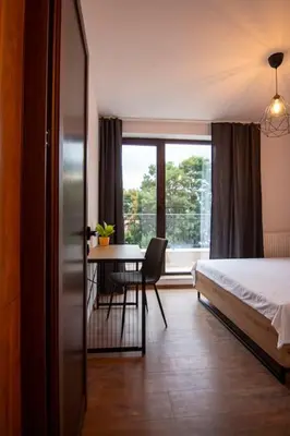 a bedroom with a bed and a table and a window at Apartment with private parking 1 in Sofia