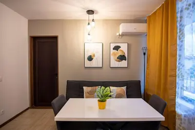 a dining room with a white table and a couch at Apartment with private parking 1 in Sofia