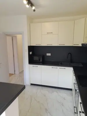 a kitchen with white cabinets and a black counter top at The white suite in Sofia