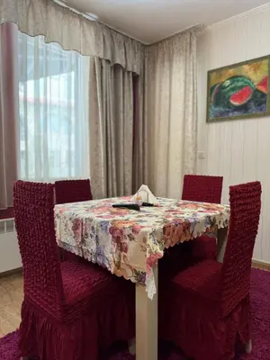 a dining room table with two chairs and a table with a floral table cloth at Grand Monastery Private Apartment in Pamporovo in Pamporovo