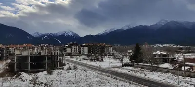 a snowy city with buildings and mountains in the background at Уютная квартира в комплексе Snow Lodge in Bansko