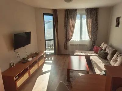 a living room with a couch and a tv at Уютная квартира в комплексе Snow Lodge in Bansko