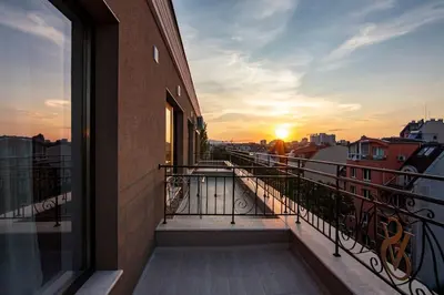 a balcony of a building with the sunset in the background at Аpartment with Free Parking in Sofia