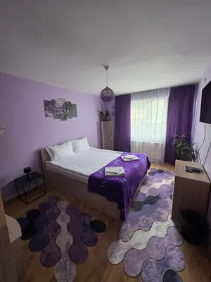 a bedroom with a large bed and a purple rug at Guest House Freya in Beli Iskar