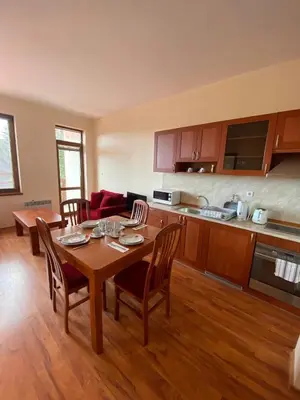 a kitchen and living room with a table and chairs at Cedar Heights Cozy Apartments in Pamporovo
