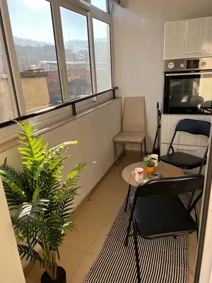 a room with a table and chairs and windows at Apartament Kamarashki in Troyan