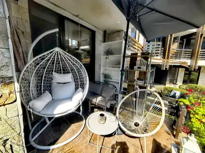 a porch with two chairs and a table and an umbrella at Garden apartment Aspen Suites A008 in Bansko