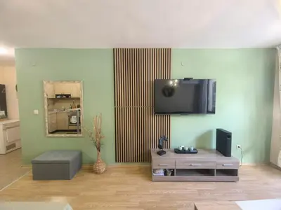 a living room with a flat screen tv on the wall at Garden apartment Aspen Suites A008 in Bansko