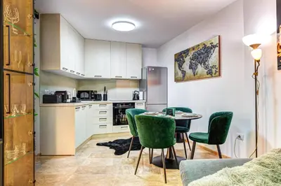 a kitchen with a table and green chairs in a room at Boutique Apartment DOLCHE VITA in Smolyan