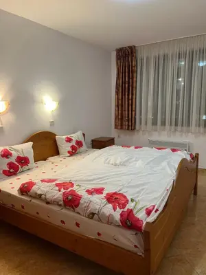 a bedroom with a bed with red flowers on it at Скиелит 5 in Pamporovo