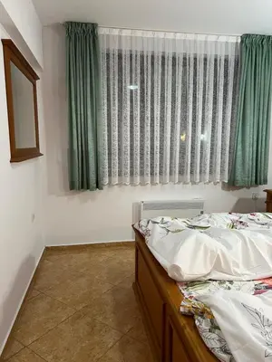 a bedroom with two beds and a window with green curtains at Скиелит 3 in Pamporovo