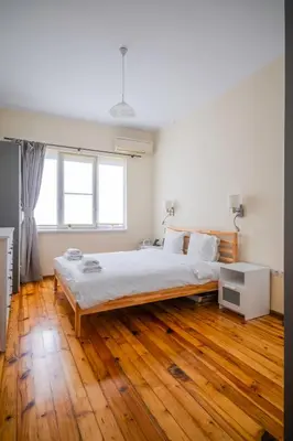 a white bedroom with a large bed and wooden floors at Stylish CityHub Retreat in Sofia Center by Flat Mаnager in Sofia