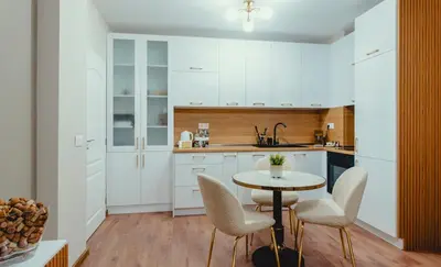 a kitchen with white cabinets and a table and chairs at Elegant Living Apartment 1 in Sofia