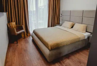 a bedroom with a bed and a chair and a window at Elegant Living Apartment 1 in Sofia