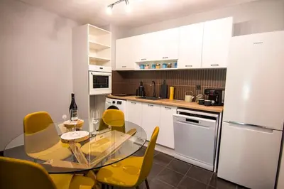 a kitchen with a glass table and yellow chairs at Аpartment near Sofia airport in Sofia