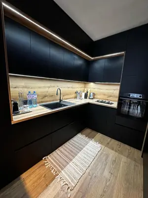 a kitchen with black cabinets and a sink and a rug at 1BR Modern condo near the University in Sofia