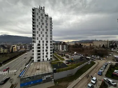 a tall white building next to a street with cars at 1BR Modern condo near the University in Sofia