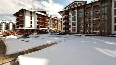 a snow covered parking lot in front of buildings at Апартамент Belvedere G106 in Bansko