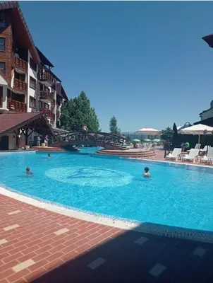a large swimming pool with people in the water at Апартамент Belvedere G106 in Bansko