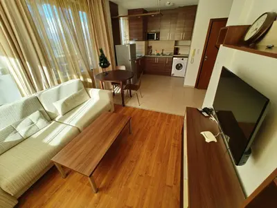 a living room with a couch and a tv and a table at Апартаменты в Belvedere in Bansko