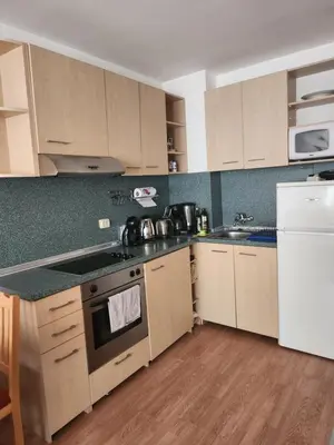 a kitchen with white appliances and wooden cabinets at One bedroom Apartment in Bansko