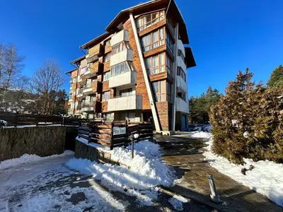 a apartment building in the snow with snow around it at Pine Tree one bedroom apartment in Bansko