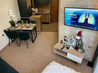 a living room with a table and a tv on a wall at Elizi winter apartments Pamporovo in Pamporovo