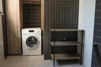 a washer and dryer in a black tiled bathroom at Вила Маунтайн Вю in Brestnik