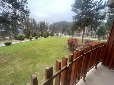 a fence in a yard with a park behind it at Nikol 3 SPA CLUB BOR in Velingrad