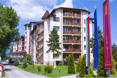 a large apartment building on a street with flags at Nikol 3 SPA CLUB BOR in Velingrad