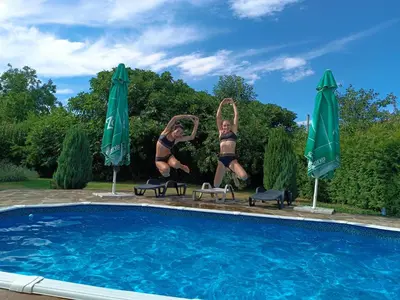 a woman and two girls doing a jump by a swimming pool at Къща за гости Вила Смокиня град Хисаря in Hisarya