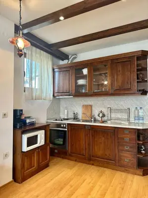 a kitchen with wooden cabinets and a stove top oven at Уникален апартамент с изглед към планината in Bansko