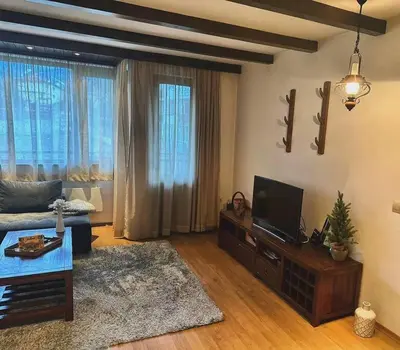 a living room with a couch and a flat screen tv at Уникален апартамент с изглед към планината in Bansko