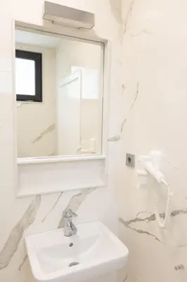 a white bathroom with a sink and a mirror at Luxury rooms 12-1 in Plovdiv