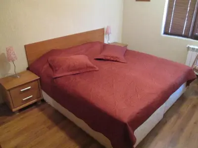a bed with a red comforter and two pillows at Comfort Private Apartments in Bansko