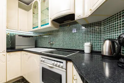 a kitchen with white cabinets and green tiles on the wall at A Nostalgic Getaway in Plovdiv's Historic Quarter by Flat Mаnager in Plovdiv