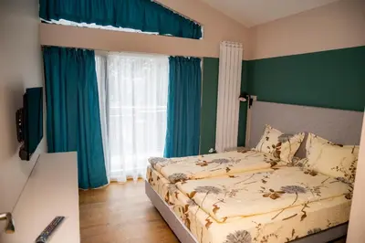 a bedroom with a bed with green walls and blue curtains at Villa Doma in Sapareva Banya