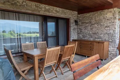 a wooden table and chairs on a screened porch with a table and windows at Martini villa Lake in Razlog