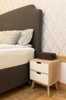 a bed with a wooden night stand next to a bed with a drawer at Luxury rooms 12-2 in Plovdiv