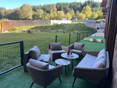 a patio with chairs and tables with a view of a field at Apart-Hotel Crown Bansko 2 in Bansko